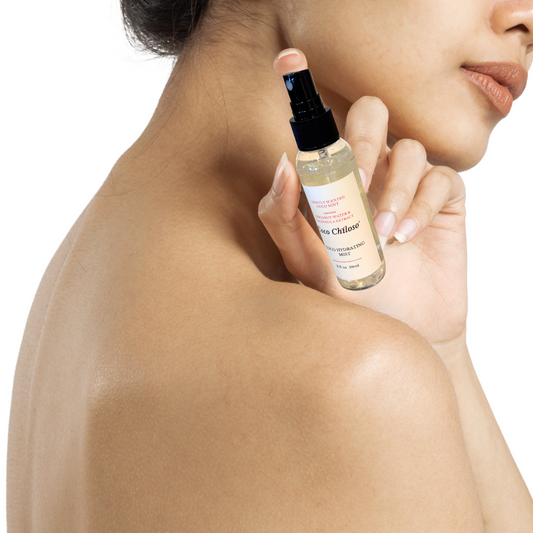 Person holding Coco Hydrating Mist bottle near their face on a white background